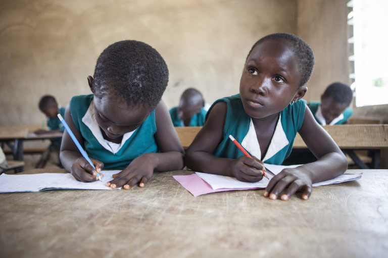 A schoolgirl looking up from her writing pad