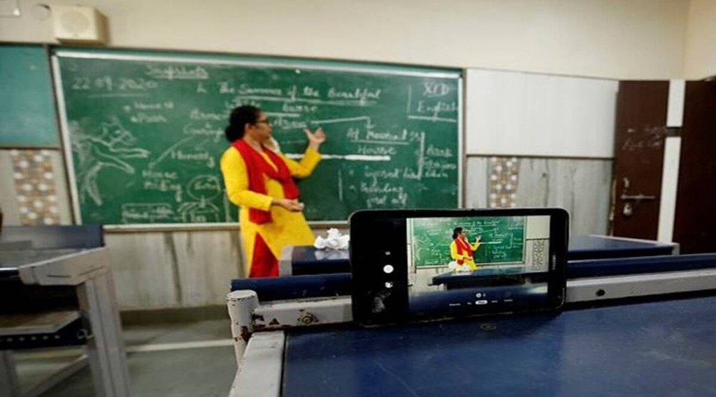 teacher stands in front of board while streaming live from a mobile phone