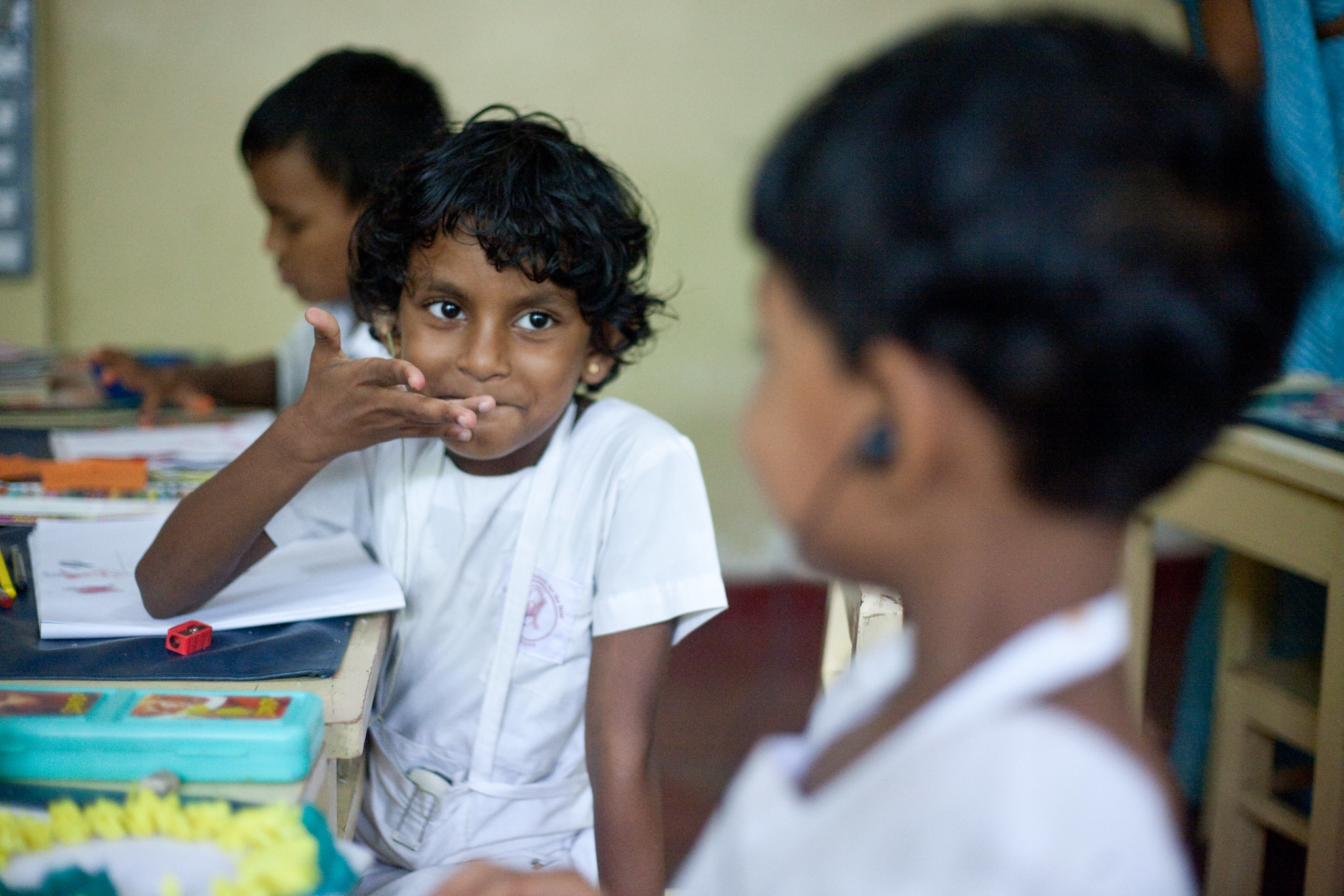 Two children use sign language in a classroom