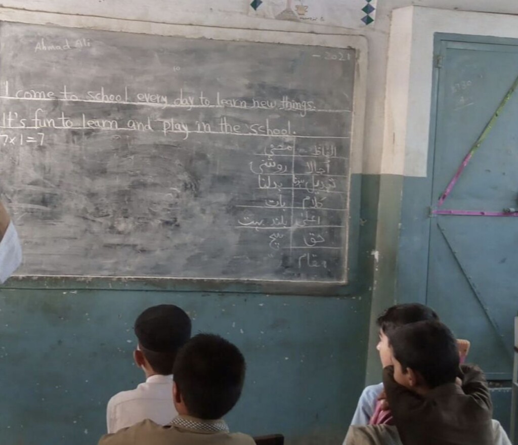 Children in school looking at whiteboard that shows the message 'I come to school every day to learn new things' written in chalk