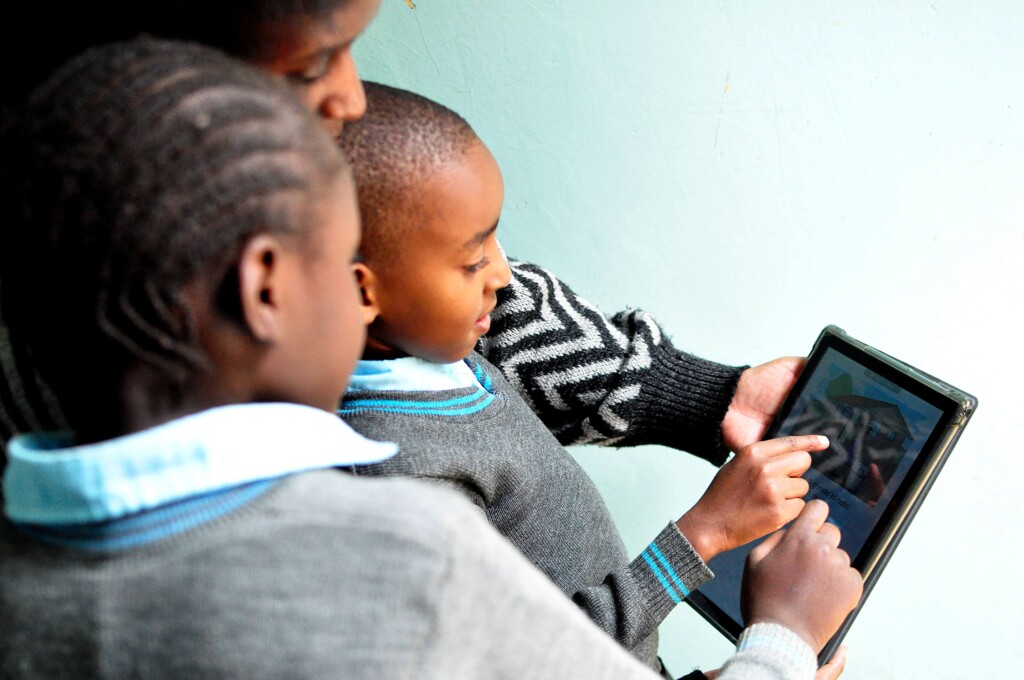 Children read from a tablet with their caregiver