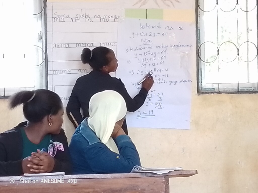 The picture shows a female teacher sharing her knowledge on a mathematical calculation with peers in a CoL. 